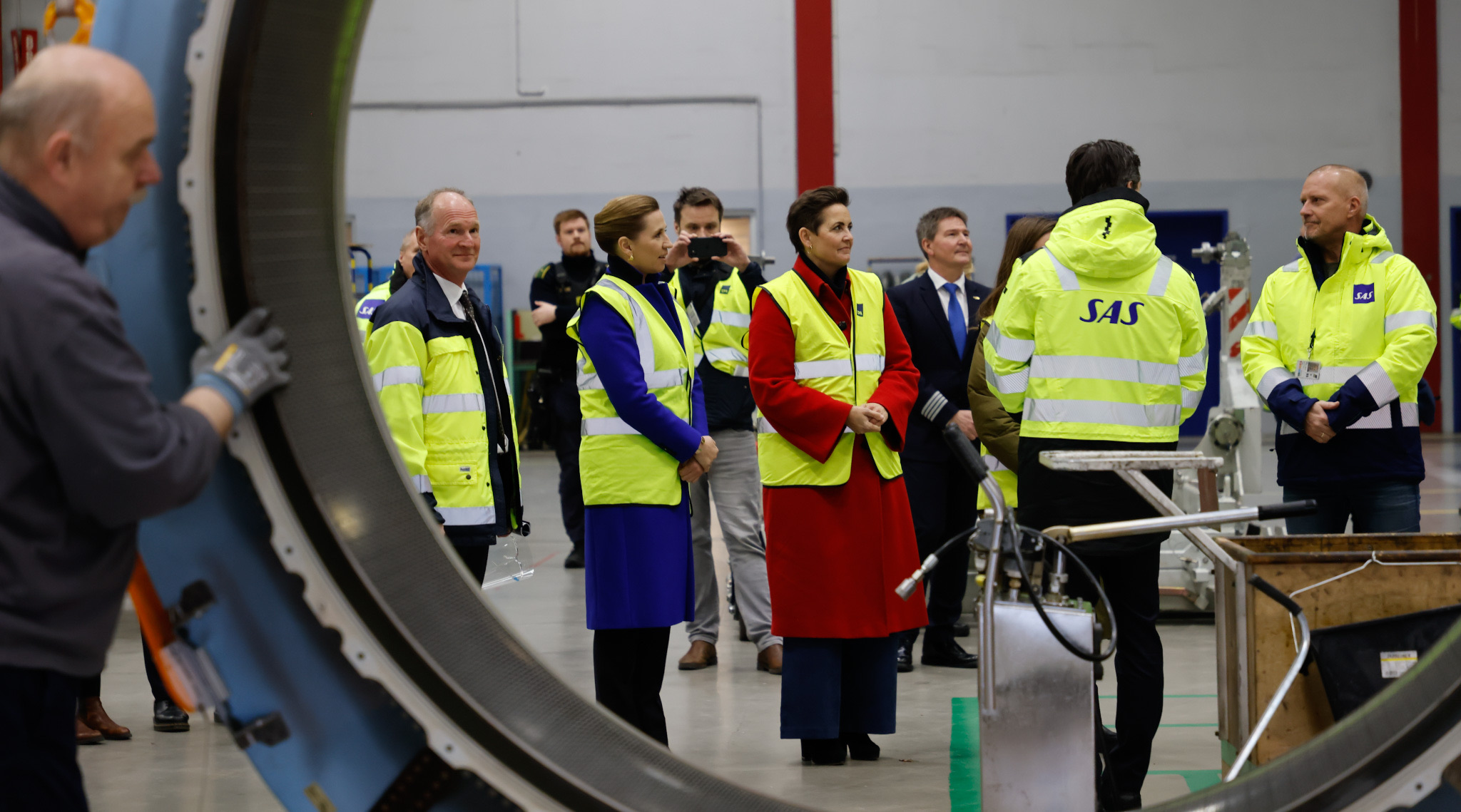 Statsminister Mette Frederiksen på besøg i Københavns Lufthavn med Pia Olsen Dyhr og Mai Villadsen - i forgrunden køres en krans fra en flymotor forbi.