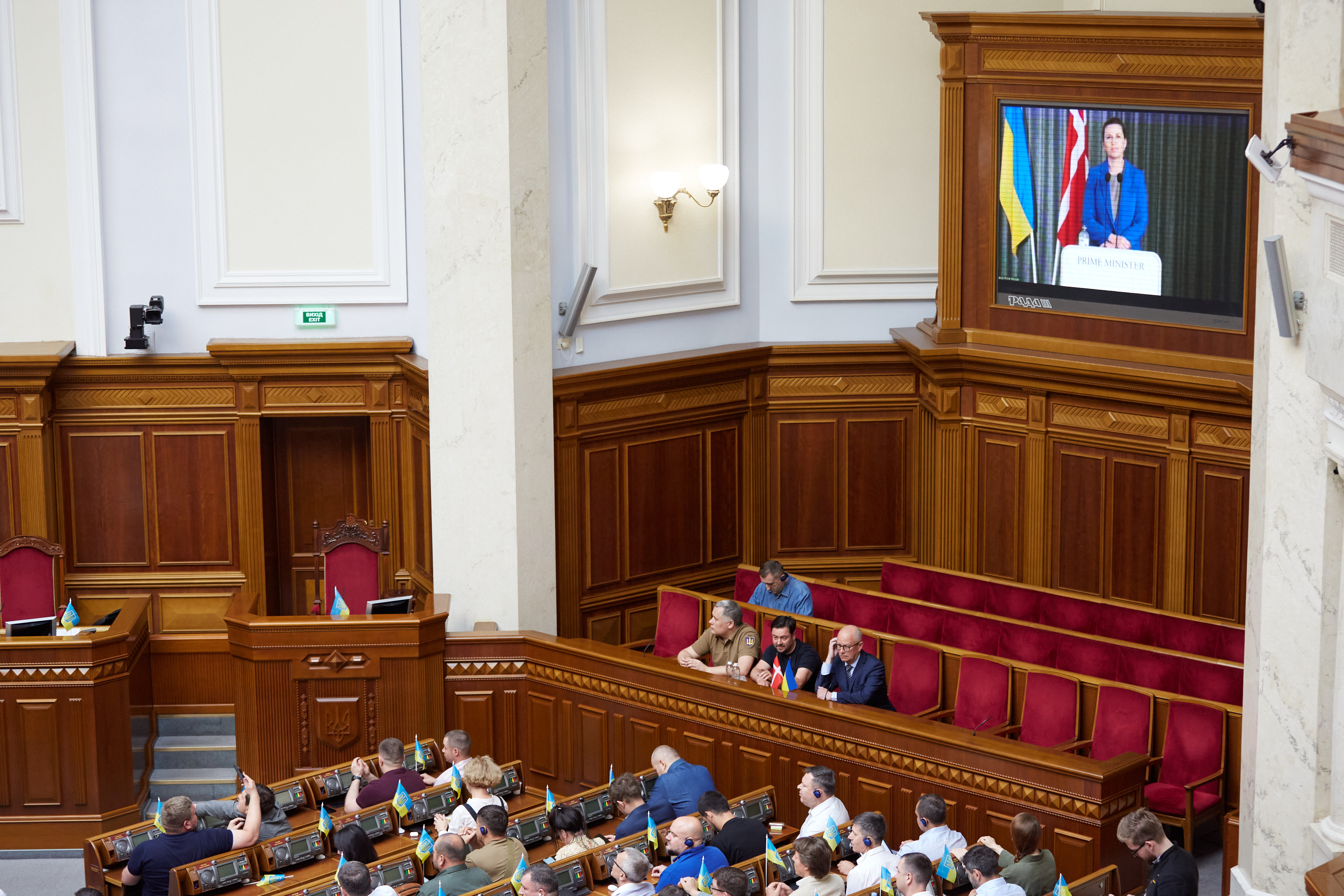 Statsminister Mette Frederiksen ses på storskærm, mens hun via videolink taler til det ukrainske parlament.